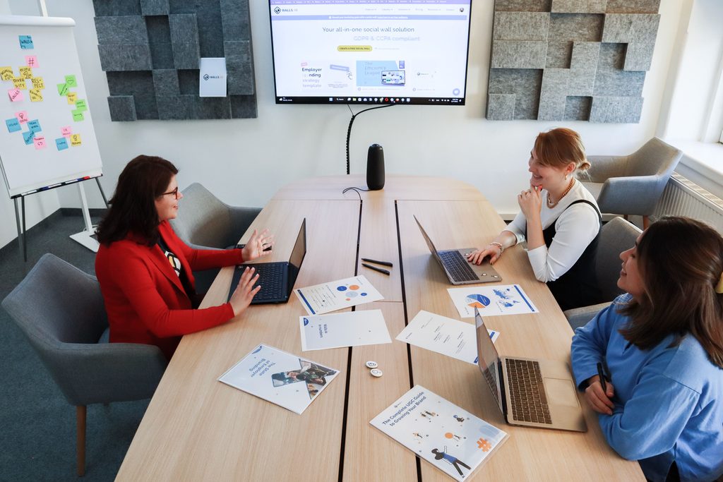 Vrouwen die aan het praten zijn achter laptop. Papieren op tafel.